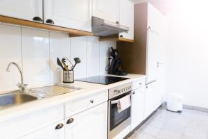 a kitchen with white cabinets and a sink at Ferienwohnung Mila in Grevenkop +3 photos