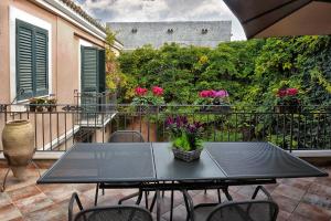 uma mesa e cadeiras numa varanda com flores cor-de-rosa em Palazzo Bella em Campobello di Licata