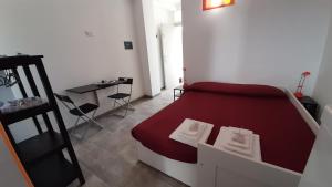 una piccola camera con letto rosso e tavolo di Regina Isabella Rooms a San Foca