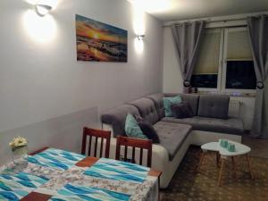 a living room with a couch and a table at Apartament Perełka Zielone Tarasy Kołobrzeg in Kołobrzeg