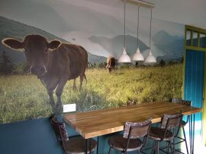 a mural of a cow in a field with a table at The Whimsy 2 bedroom cottage in National Forest, private parking & garden in Blackfordby