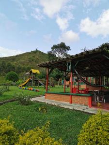 un parque con un parque infantil con una colina al fondo en Finca La Playa Ecohotel - Experiencia Campestre -, en Salento