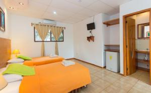 two twin beds in a room with a tv at Hotel Twin Galápagos in Puerto Ayora