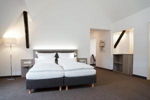 ein Schlafzimmer mit einem großen Bett mit weißen Kissen in der Unterkunft Hünerbein's Posthotel in Schledehausen