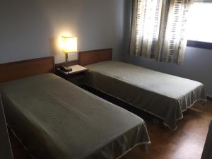 a hotel room with two beds and two lamps at São Roque Hotel & Suites in Bragança