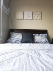 uma cama com lençóis brancos e almofadas num quarto em Cozy on the 28th! IT Park Cebu City em Cebu