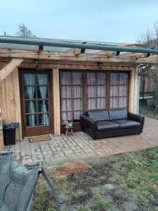 a black couch on a patio with a pergola at Édes Otthon Vendégház in Nagybörzsöny