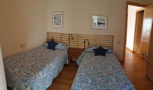 タラゴナにあるAPARTAMENT CASA CORDERETのベッドルーム(青い掛け布団付きのベッド2台付)