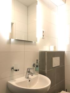 ein Bad mit einem Waschbecken und einem Spiegel in der Unterkunft Holiday Apartments House in Essen