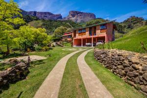 een huis op een heuvel met een stenen muur bij Hospedaria Estação Píccola No quintal da Pedra do Baú in São Bento do Sapucaí