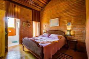 um quarto com uma cama numa parede de tijolos em Hospedaria Estação Píccola No quintal da Pedra do Baú em São Bento do Sapucaí
