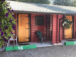 a red cabin with a door and two chairs on a porch at Miette Hot Springs Bungalows in Jasper