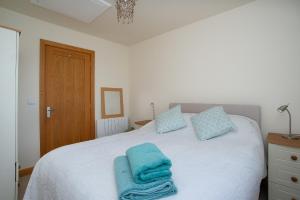 ein Schlafzimmer mit einem Bett mit blauen Handtüchern darauf in der Unterkunft Finest Retreats - Sea Views Cottage in Prestatyn