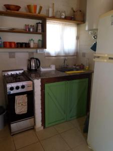 cocina con fogones y puerta verde en Cabaña Refugio De Caminantes in 