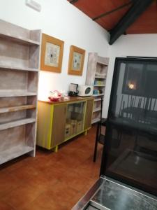a living room with a tv and a counter with shelves at ALBERGUE TURÍSTICO DE CORNALVO in Trujillanos