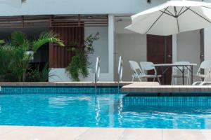 a swimming pool with a table and an umbrella at Fiori Apartments in Santa Cruz de la Sierra