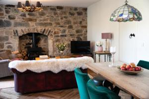 a living room with a table and a stone wall at Dandaleith Cottage No.1 in Craigellachie