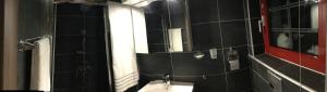 a black tiled bathroom with a sink and a mirror at Mario’s house in Vergina