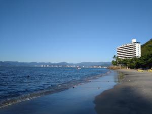 Blick auf einen Strand mit einem Gebäude und dem Meer in der Unterkunft Casa Beira-Mar 10pessoas 3 Suítes Térreo - A única realmente "Pé na Areia" c WiFi in Caraguatatuba