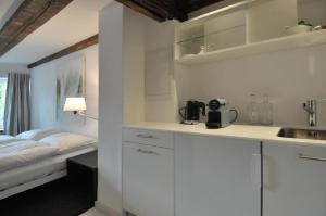 una cocina con armarios blancos y una cama en una habitación en Röschenzerhof en Röschenz