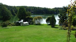 a large grassy yard with a house on the shore of a lake at Rinne in Rymättylä