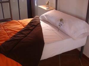 Una cama con sábanas blancas y una planta. en ALBERGUE TURÍSTICO DE CORNALVO, en Trujillanos