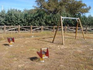 trois balançoires dans un champ à côté d'une clôture dans l'établissement ALBERGUE TURÍSTICO DE CORNALVO, à Trujillanos