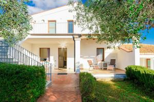 a white house with a patio and trees at I Girasoli in Bari Sardo