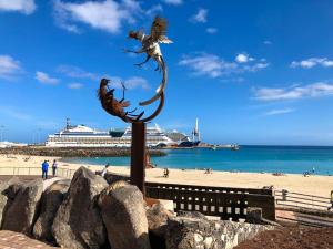 a statue of a bird on a pole next to a beach at Duplex playa chica in Puerto del Rosario