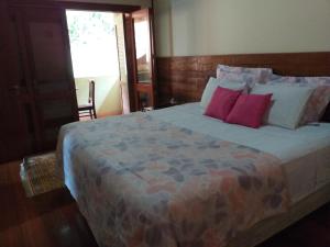 - une chambre avec un grand lit et des oreillers rouges dans l'établissement Linda casa na Serra da Cantareira, à Mairiporã