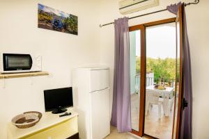 a room with a refrigerator and a television and a balcony at I Girasoli in Bari Sardo