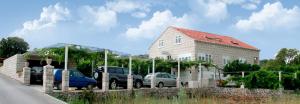 a building with cars parked in a parking lot at Pansion Marinka-Bire Rooms in Lumbarda