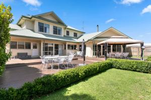 a house with a deck with a table and chairs at SEA BREEZE on THE CRESCENT in Inverloch