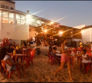 una mujer caminando en la arena frente a un restaurante en Apartamentos da Coló, en Arembepe