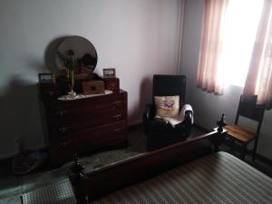 una stanza con una sedia, un comò e uno specchio di Adega Ilhéu a Feteira