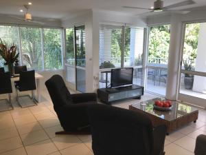 salon z telewizorem, krzesłami i stołem w obiekcie Secluded tropical apartment w mieście Palm Cove