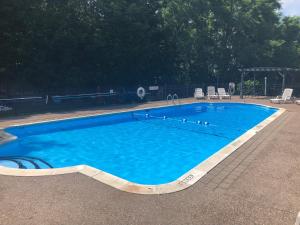 a large blue swimming pool with chairs in a yard at West Winds Motel & Cottages in Clayton