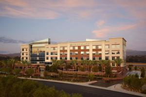 a large white building with palm trees in front of it at Hyatt Place Las Vegas at Silverton Village in Las Vegas