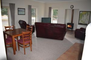 sala de estar con mesa, sillas y sofá en Gladstone Cottage en Twizel