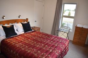 ein Schlafzimmer mit einem großen Bett und einem Fenster in der Unterkunft Gladstone Cottage in Twizel