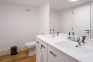 La salle de bains blanche est pourvue de toilettes et d'un lavabo. dans l'établissement Beautiful 3-Story house in Chiado with a 40m² private terrace, à Lisbonne