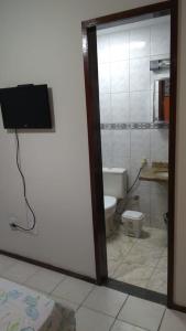 a bathroom with a toilet and a tv on the wall at Cobertura Aconchegante Itaúna in Saquarema +28 photos