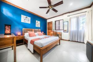 a bedroom with blue walls and a bed and a desk at The Beach House Carabao Island in San Jose