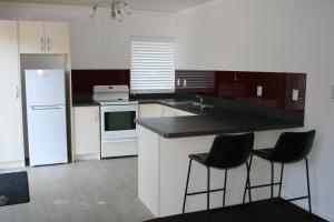 a kitchen with white cabinets and black counter tops at Bridgehaven Guesthouse in Okoroire