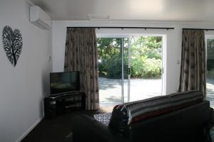 a living room with a couch and a sliding glass door at Bridgehaven Guesthouse in Okoroire