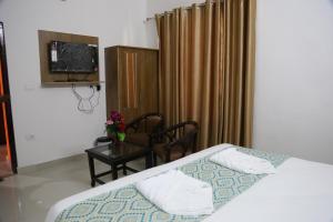 a bedroom with a bed and a chair and a television at HOTEL YOG TAPOVAN- Rafting Available in Rishīkesh