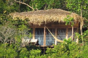 eine Hütte mit einem Strohdach und einer Hängematte in der Unterkunft Alta Vista Amazon Lodge in Manacapuru