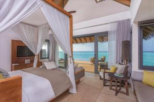 a bedroom with a bed and a view of the ocean at Vakkaru Maldives - Luxury Private Island Resort in Baa Atoll