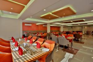 ein Restaurant mit Tischen und Stühlen mit roten Servietten in der Unterkunft MAREENA in Kottayam