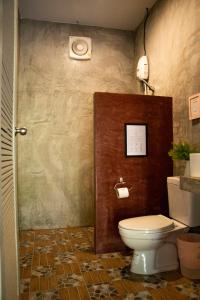 a bathroom with a toilet and a wall at Raven Blue in Ko Lanta